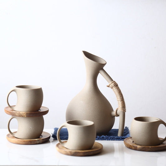 Handmade pottery cold kettle set with 4 ceramic cups and wooden saucers on white background