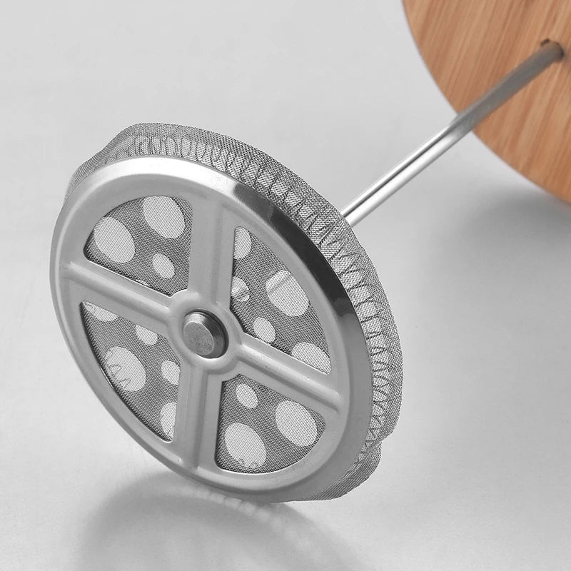 Metallic french press inner wheel with a wooden handle on a light gray background