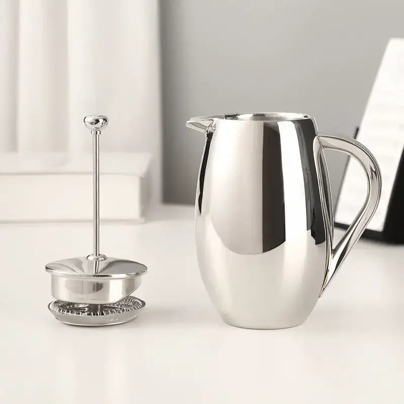 Stainless steel french press pitcher and press toole strainer on a white surface with a neutral background