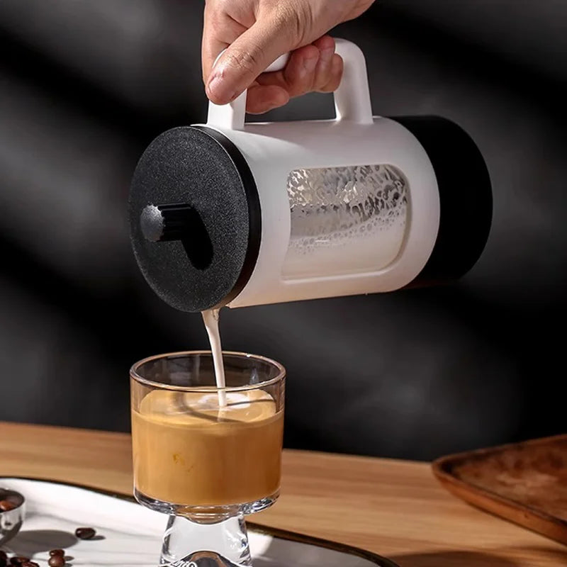 Person pouring coffee from a French press into a glass on a wooden surface.