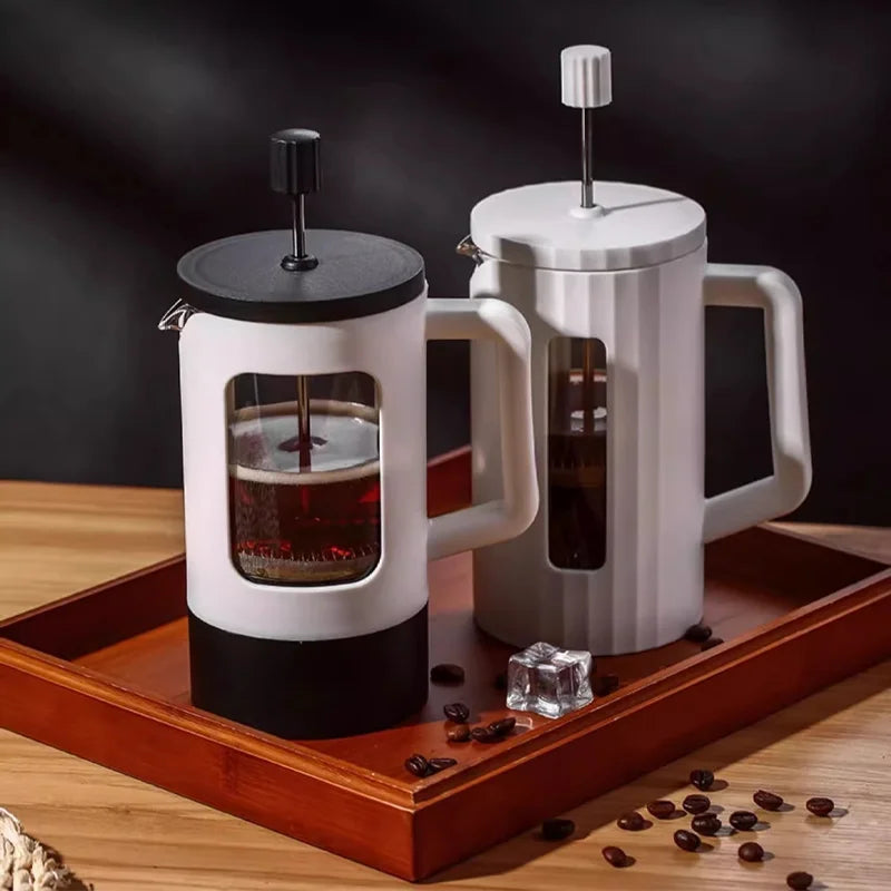 Two French press coffee makers on a wooden tray with coffee beans and ice cubes.