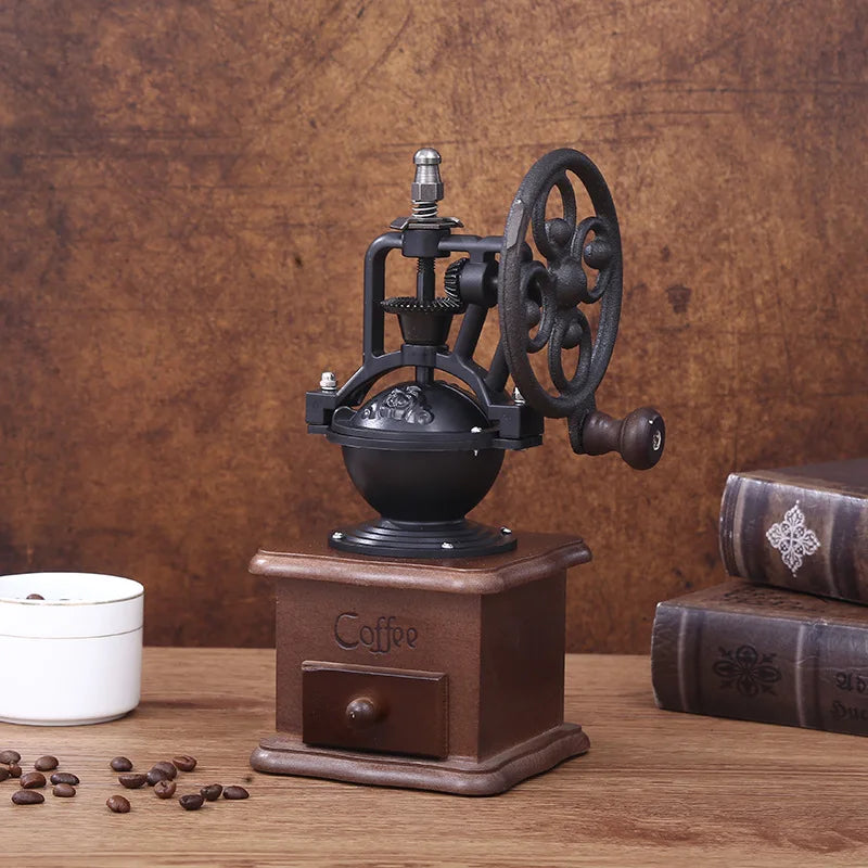 Vintage-style coffee grinder on a wooden surface with coffee beans and a book in the background.