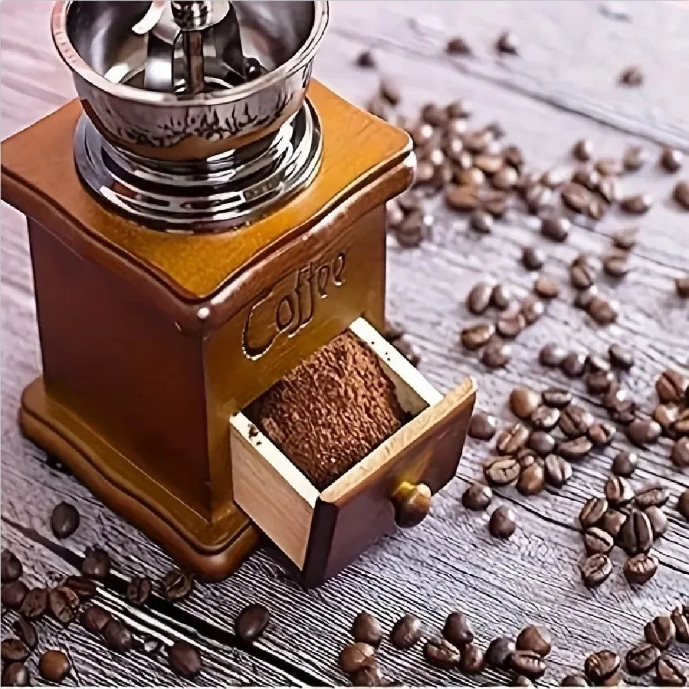 Manual coffee grinder with ground coffee and coffee beans on a wooden surface